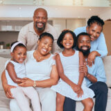 Happy black family, portrait smile and sofa relaxing together for quality bonding or break at home. Mother, father and grandparents with kids smiling in relax for family time on living room couch.